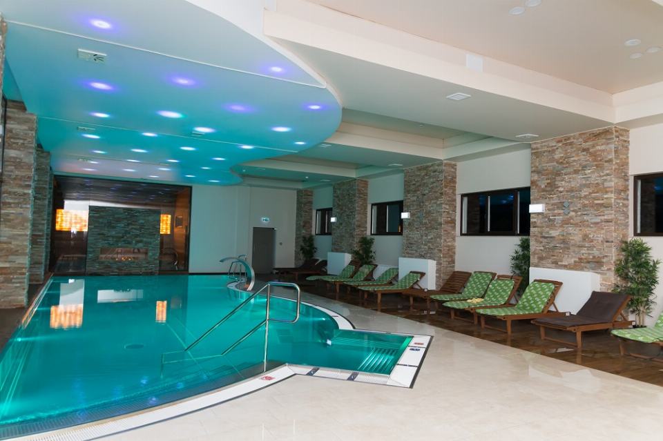Piscina interioară din inox, cu șezlonguri și perete de piatră, la Centrul Spa Lidana