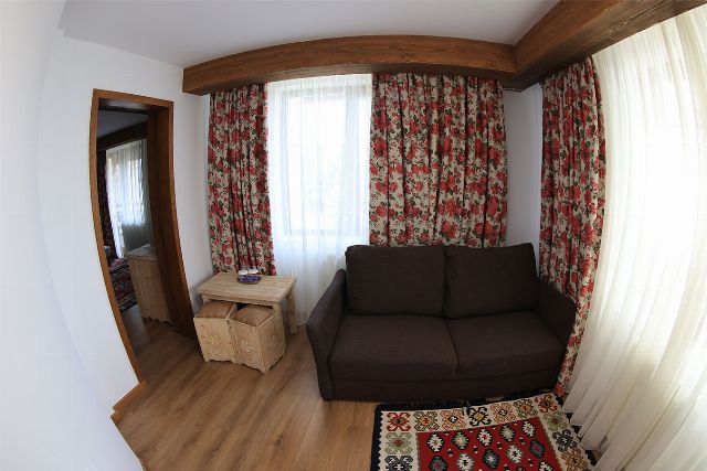 Spațiul de zi al apartamentului 1 din Vila Rebeca, cu canapea, televizor și fereastră mare