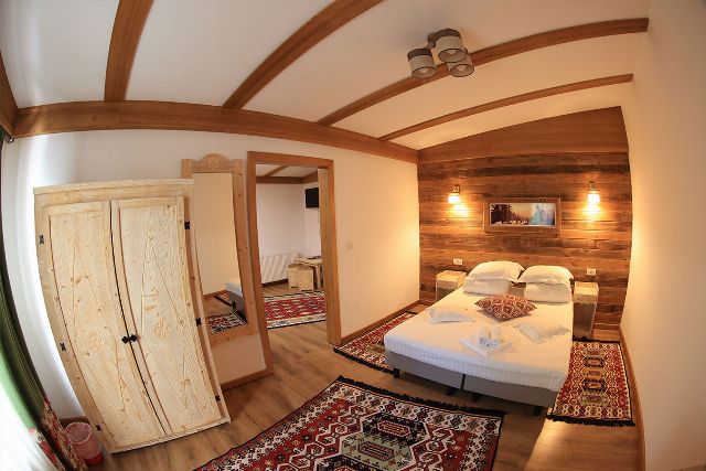 Apartamentul 2 din Vila Rebeca, văzută dinspre ușă, cu pat matrimonial și canapea extensibilă și noptiere de lemn masiv
