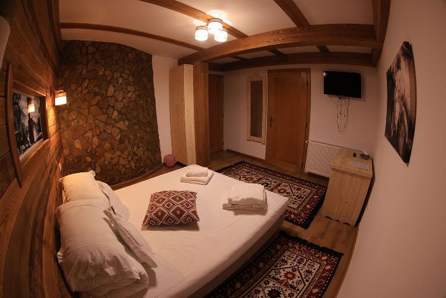 Apartamentul 3 din Vila Rebeca, văzută dinspre ușă, cu pat matrimonial și canapea extensibilă și noptiere de lemn masiv