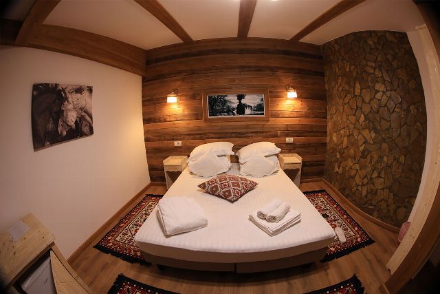 Apartamentul 3 din Vila Rebeca, cu pat matrimonial și canapea extensibilă, veioze de perete și fereastră cu perdele deschise