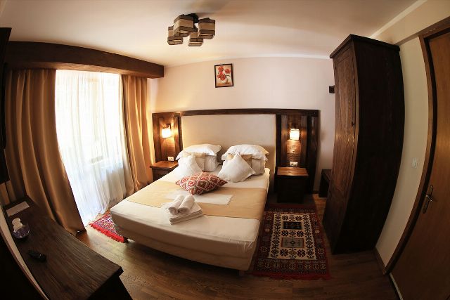 Camera 1 din Vila Rebeca, cu pat matrimonial, lambriu de lemn și covor tradițional bucovinean