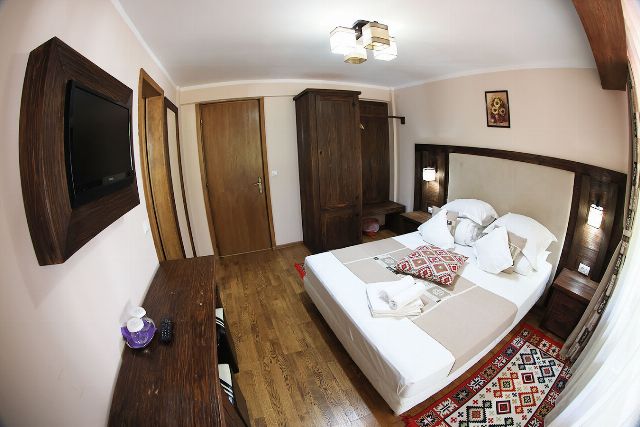 Camera 2 din Vila Rebeca, cu pat matrimonial, lambriu de lemn și covor tradițional bucovinean