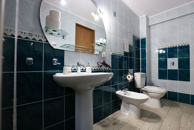 Baia proprie a camerei 2 din Vila Rebeca, cu duș, chiuvetă și faianță decorativă