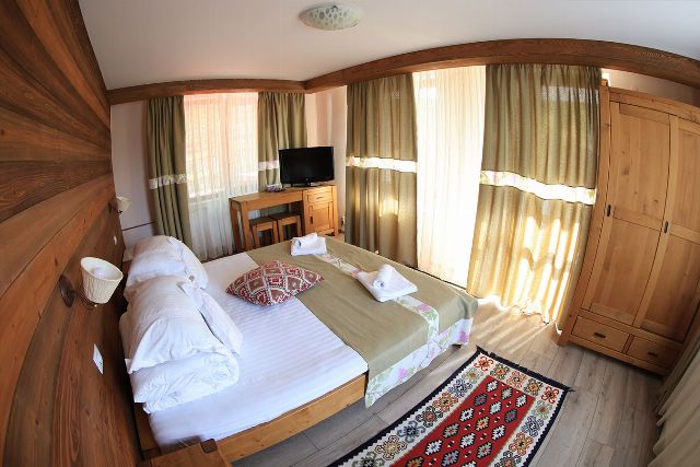 Camera 3 din Vila Rebeca, văzută dinspre ușă, cu pat matrimonial și noptiere de lemn masiv