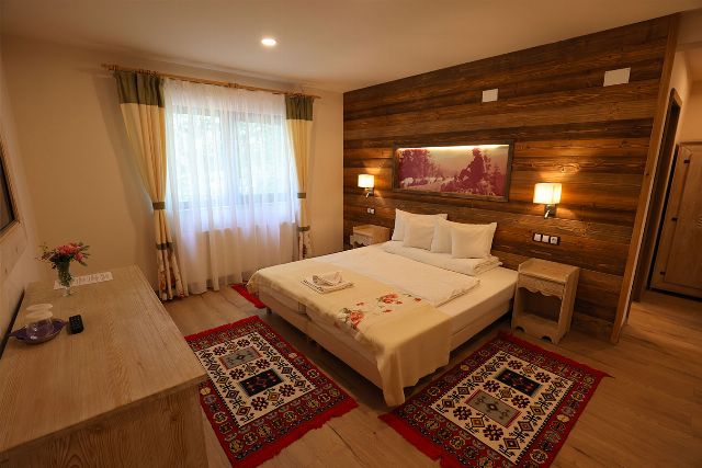 Camera 1 din Vila Savel, cu două paturi twin, lambriu de lemn și covor tradițional bucovinean