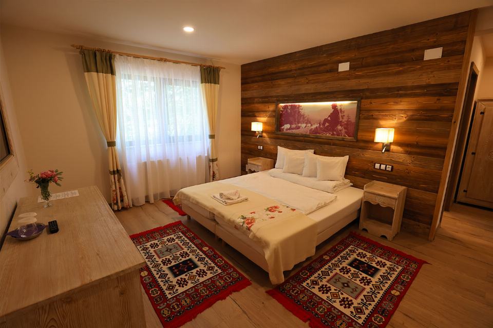 Camera 1 din Vila Savel, cu două paturi twin, lambriu de lemn și covor tradițional bucovinean
