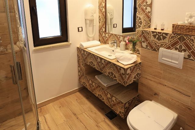 Baia proprie a camerei 1 din Vila Savel, cu duș, chiuvetă și faianță decorativă
