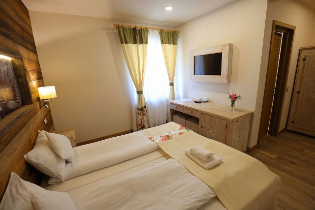 Camera 2 din Vila Savel, cu două paturi twin și canapea, lângă fereastra spre pădure