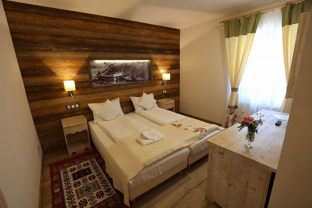 Camera 2 din Vila Savel, cu două paturi twin, lambriu de lemn și covor tradițional bucovinean