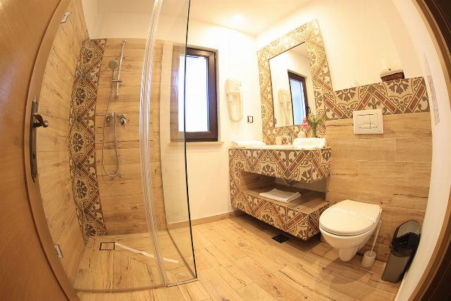 Baia proprie a camerei 2 din Vila Savel, cu duș, chiuvetă și faianță decorativă