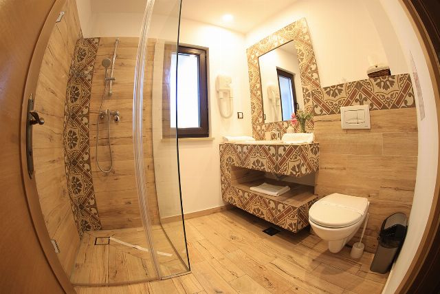 Baia proprie a camerei 4 din Vila Savel, cu duș, chiuvetă și faianță decorativă