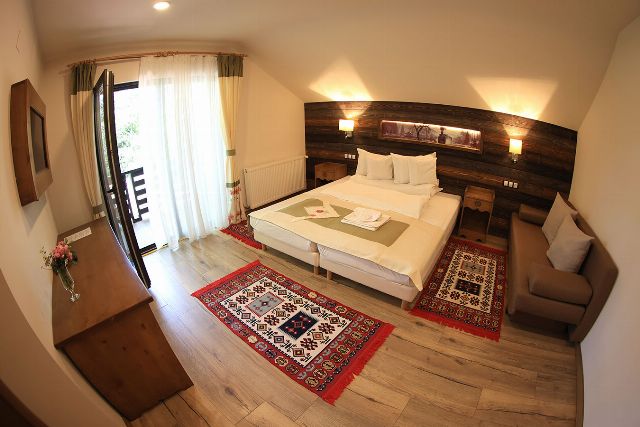 Camera 6 din Vila Savel, cu două paturi twin, lambriu de lemn și covor tradițional bucovinean