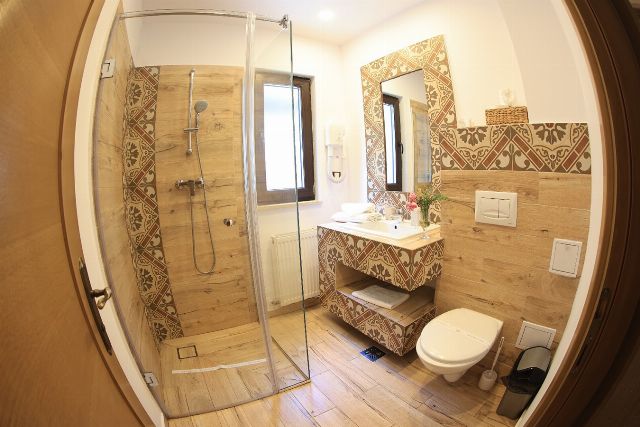 Baia proprie a camerei 7 din Vila Savel, cu duș, chiuvetă și faianță decorativă