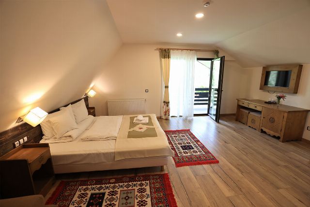 Camera 8 din Vila Savel, cu două paturi twin, lambriu de lemn și covor tradițional bucovinean
