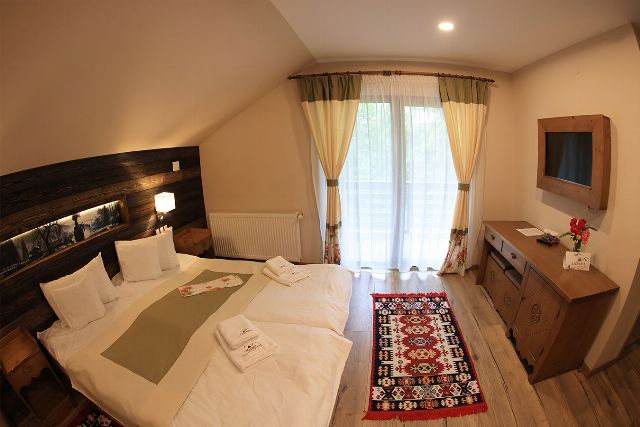 Camera 4 din Vila Zamfira, cu două paturi twin, birou de lemn și televizor cu ecran plat