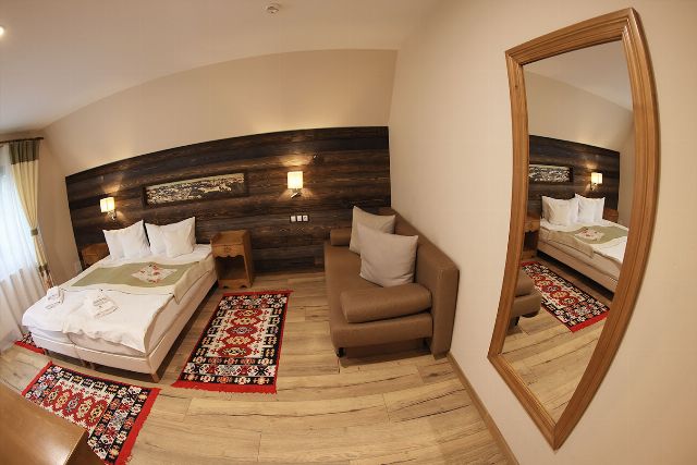 Camera 5 din Vila Zamfira, cu două paturi twin, lambriu de lemn și covor tradițional bucovinean